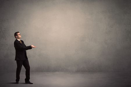 Caucasian businessman standing in front of a grunge, blank wall