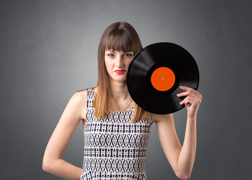 Young lady holding vinyl record on a grey background
