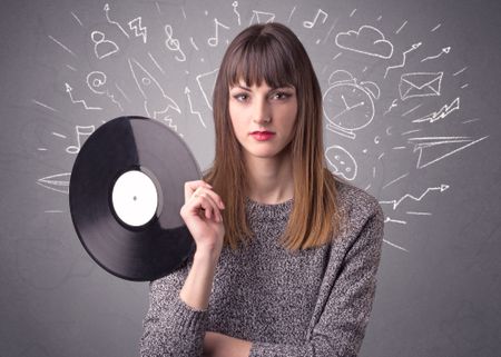 Young lady holding vinyl record on a grey background with mixed scribbles behind her