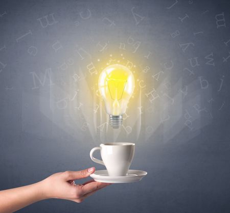 Young female hand holding coffee cup with a lightbulb and alphabet letters above it 