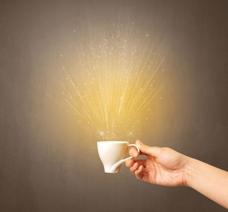 Young female hand holding coffee cup with a beam of light rising out of it 