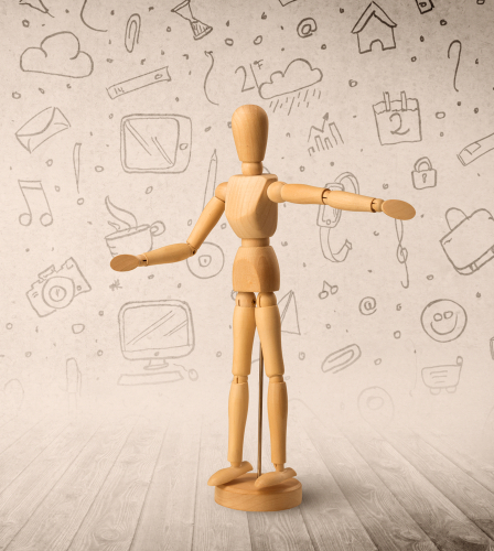 Wooden mannequin posed in front of a greyish background with mixed media scribbles behind it
