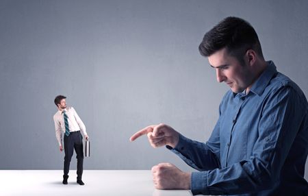 Young professional businessman being angry with an other miniature businessman