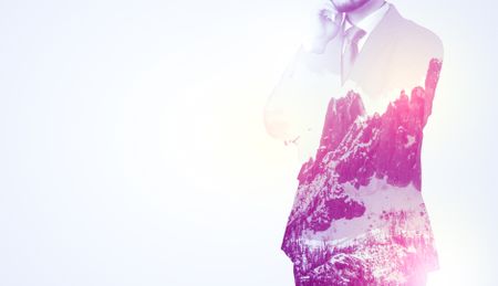  Young businessman in suit standing with sunny snowy mountain and trees graphic.