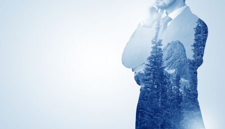 Young businessman standing and meditate with trees on the background 