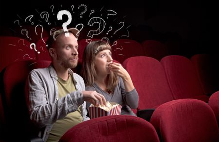 Nice couple in cinema with drawn question signs around