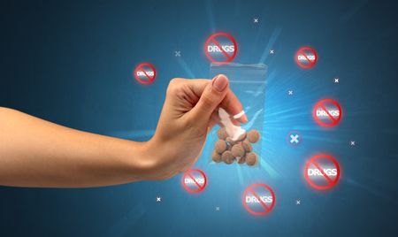 Hand giving pills with anti-drug concept and not allowed signs around