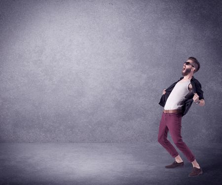 A hipster guy in stylish clothes shouting in front of an empty urban concrete wall background concept