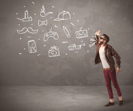 A funny hipster person in casual urban clothing shouting drawn everyday items like camera, tie or pen on city wall concept