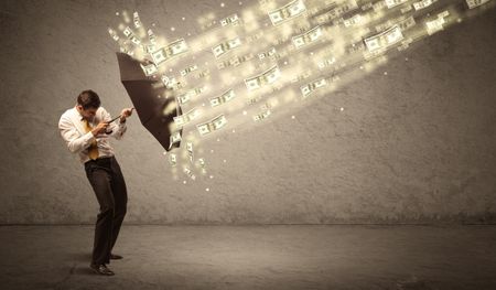 Business man holding umbrella against dollar rain concept on grungy background