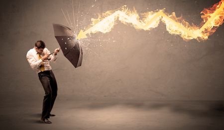 Business man defending himself from a fire arrow with an umbrella on grungy background