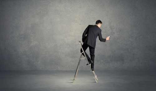 A man standing on ladder drawing with chalk in his hand on clear wall pattern background