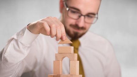 Young handsome businessman using wooden building blocks 