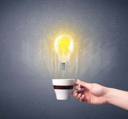 Young female hand holding coffee cup with a lightbulb and alphabet letters above it 