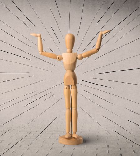 Wooden mannequin posed in front of a greyish background with black lines around him
