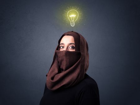 Young muslim woman wearing niqab with lit lightbulb above her head