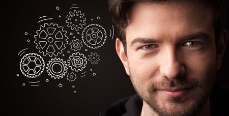 Portrait of a young businessman with rotating gears next to him on a dark background