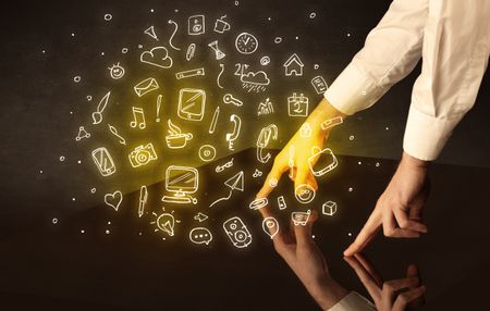 Male hands touching interactive table with yellow mixed media icons on it