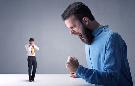 Young professional businessman being angry with an other miniature businessman 