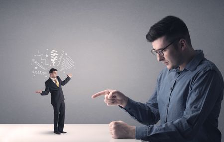 Young professional businessman being angry with an other miniature businessman who has scribbles above his head
