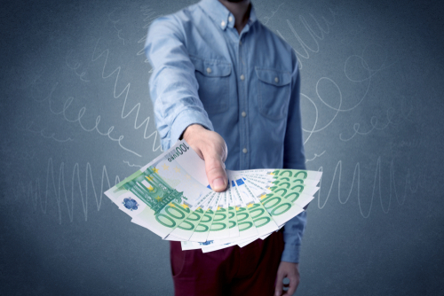 Young businessman holding large amount of bills with grungy background