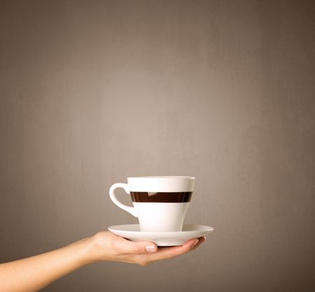 Young female hand holding coffee cup with brown background