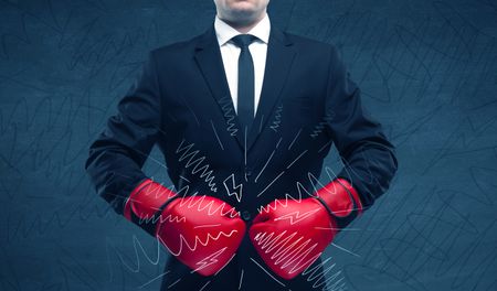 A confident businessman standing in red boxing gloves on his hand in front of blue wall background with drawn strength lines illustration concept.