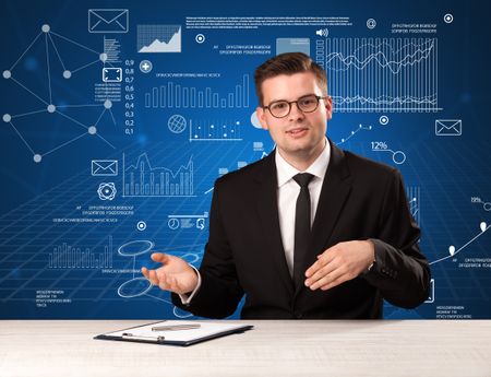 Young handsome businessman sitting at a desk with blue charts and data behind him