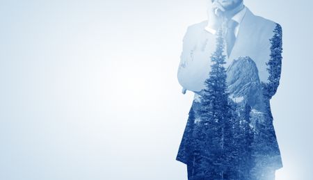 Young businessman standing and meditate with trees on the background 