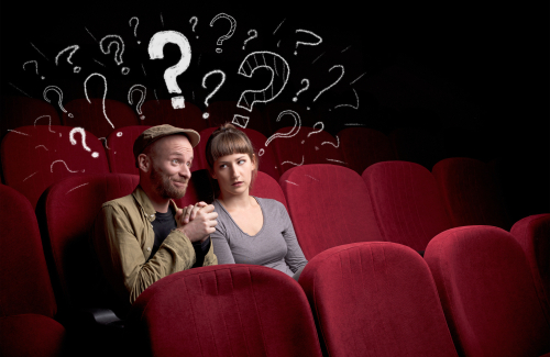 Nice couple in cinema with drawn question signs around