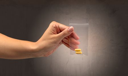 Naked, female hand giving drugs in plastic bag