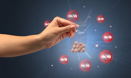 Hand giving pills with anti-drug concept and not allowed signs around