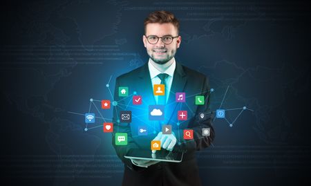 Handsome businessman in suit with tablet on his hand and application icons above
