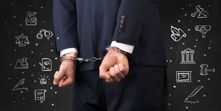 Chalk drawn courthouse symbols and close handcuffed hands in suit
