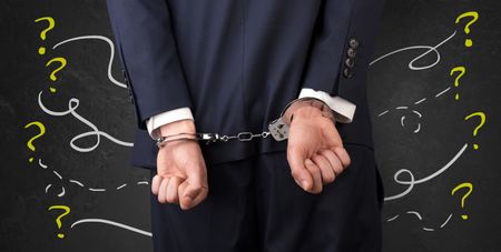 Now arrested men with handcuffs and chalk drawn question signs and lines around
