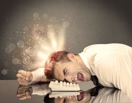 A young depressed business person laying his head on computer keyboard with thoughts exploding from his head illustrated by light beams concept