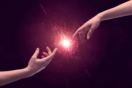 White caucasian male hands reaching out with fingers almost touching in bright red light sparkle in empty space background concept