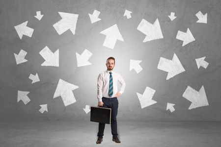 Handsome businessman standing in front of a wall with chalk drawn arrows