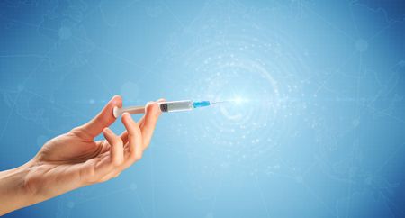 Female doctor hand holding syringe with blue background and shine