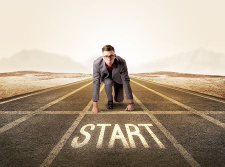 Young determined businessman kneeling before start line