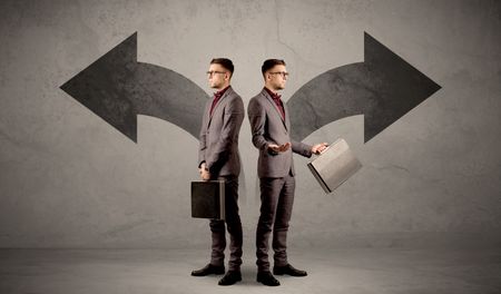 Young conflicted businessman choosing between two directions represented by black arrows