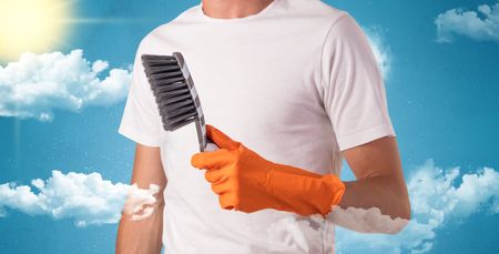 Sunny and cloudy concept with male housekeeper and orange gloves on his hand