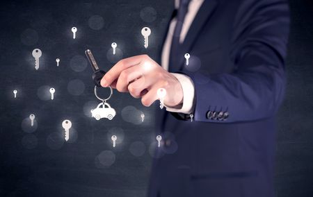 Businessman in suit holding keys with keys graphics around and dark background