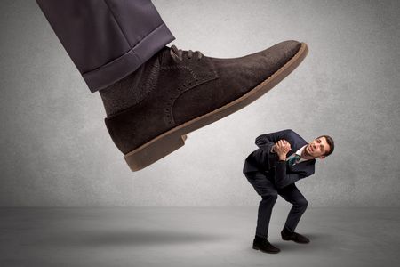 Employee is afraid of the big boss foot, which is stepping down him
