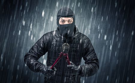 Burglar in action in black clothes with rainy concept. 