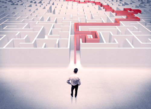 A businessman in suit giving thumbs up in front of labyrinth with red line showing the way out