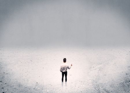 An adult elegant businessman standing in the middle of nowhere in empty grey concrete space background concept