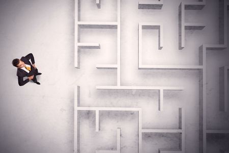 Confused businessman standing at a maze wall with grungy background