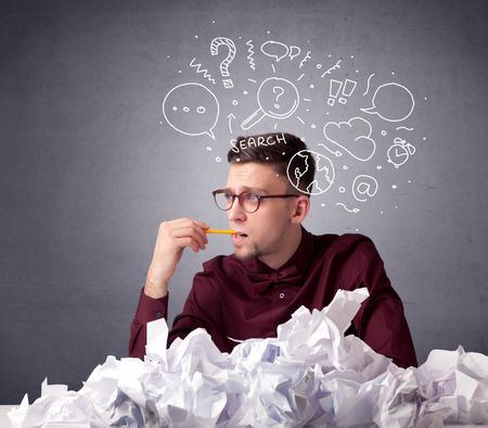 Young businessman sitting behind crumpled paper with mixed doodles over his head