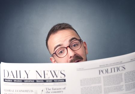 Young smart businessman reading daily newspaper